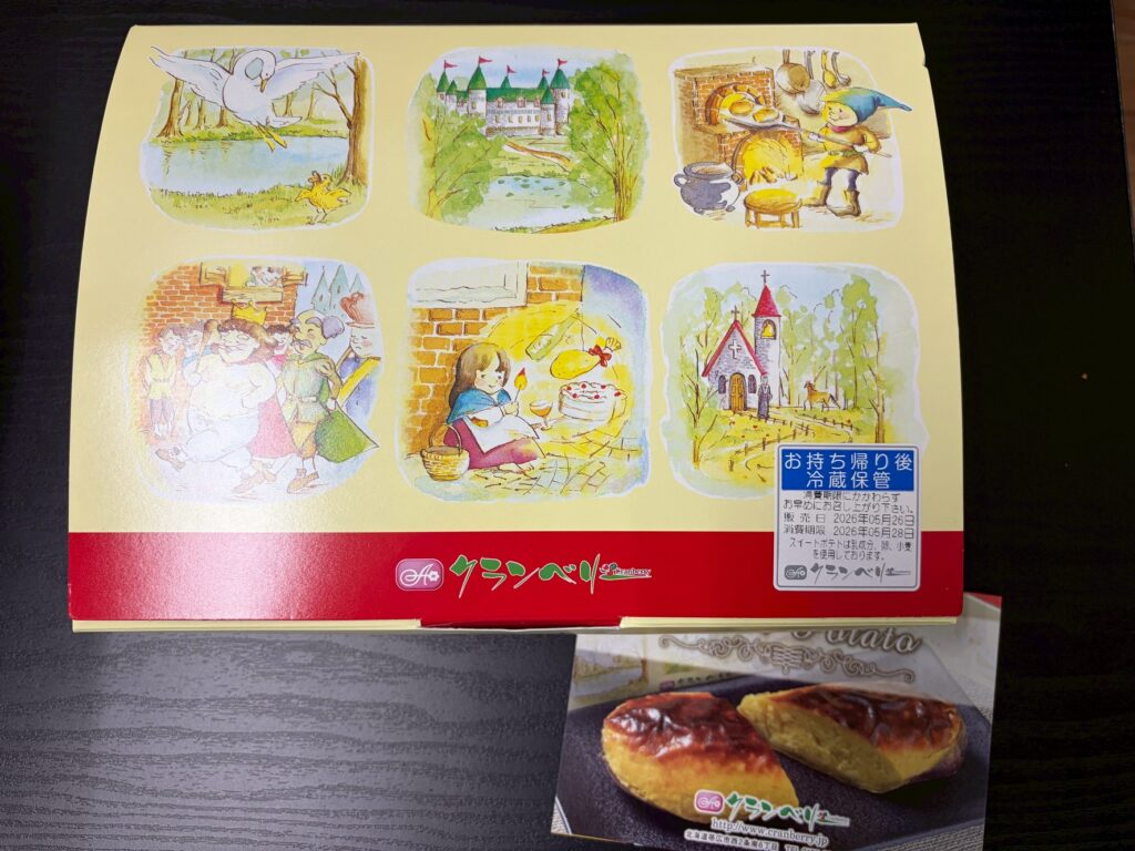 Six watercolor-style illustrations on a pale yellow packaging: a bird by a pond, a forested castle, a baker at a brick oven; a crowded scene, a girl with cake, and a church in the trees. A blue Japanese label overlaps the lower right; a red brand band runs across the bottom.
