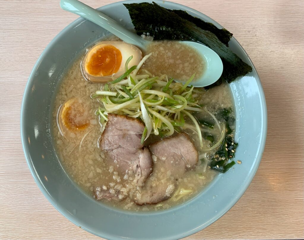 line_oa_chat_260730_171830 - 札幌の注文住宅なら寿建設|屋上庭園とガレージが得意な工務店 Bowl of ramen with sliced pork, half a soft-boiled egg, green onions, and nori seaweed in creamy broth.
